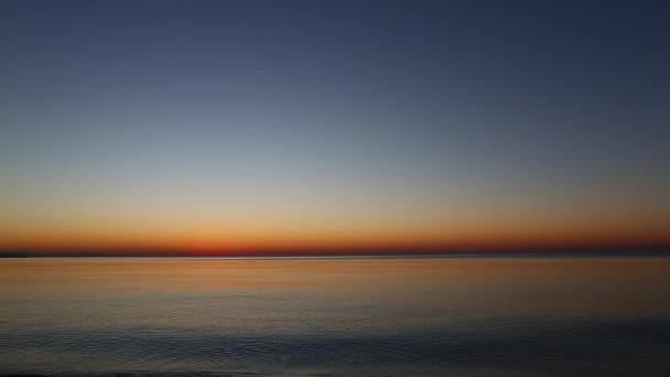 Spokojne morze na wschód słońca. małe fale rolki na brzegu morza z kamyków. — Wideo stockowe