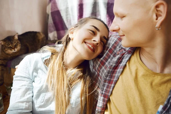 Närbild porträtt av unga anbud lackerade par sitter på golvet, flicka som ligger på hennes pojkvänner skuldra. söt katt liggande på soffa. — Stockfoto