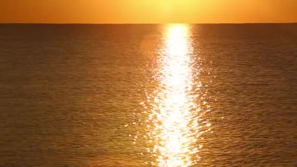 Wschód słońca nad spokojnym morzem. Słońce wschodzi tuż nad morzem i duży piękny promień odbija się na powierzchni wody — Wideo stockowe