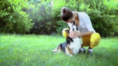 parkta parlak yeşil hamak yalan sevimli Galler Corgi köpek ile genç güzel gülümseyen kadın