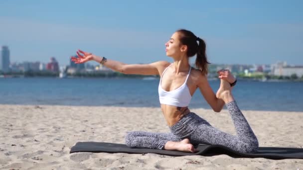 Venkovní portrét relaxační mladé dívky, která sedí sama v klidném jóga ve městě a na modrém nebi. mladá fitness dáma smíšená rasa asijské kavkazské etnického původu na pláži — Stock video