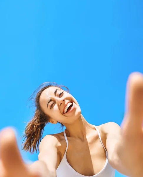 Portrett av en vakker, lykkelig kvinne som tar en selfie på kameratelefonen med blå himmel i bakgrunnen. Sommer- og fritidsbegrep . – stockfoto