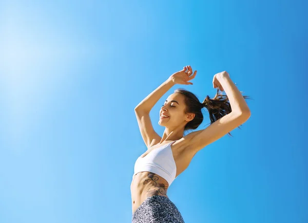 Mujer sonriente feliz con cuerpo delgado bronceado y tatuaje posando contra el cielo azul . — Foto de Stock