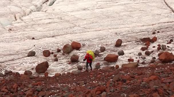 Vermoeide wandelaar met grote zware rugzak beweegt van gletsjer naar Moraine. de mens gaat langs een ruw rotsachtig parcours op Moraine. wandelen en volgen in Bergen — Stockvideo