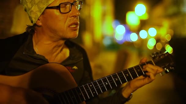 Músico callejero toca guitarra en la calle por la noche . — Vídeo de stock