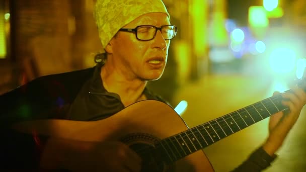 Уличный музыкант играет на гитаре на улице ночью . — стоковое видео