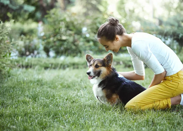 Welsh Corgi Pembroke สุนัขและยิ้ม ผู้หญิงมีความสุขร่วมกันในสวนสาธารณะกลางแจ้ง . — ภาพถ่ายสต็อก