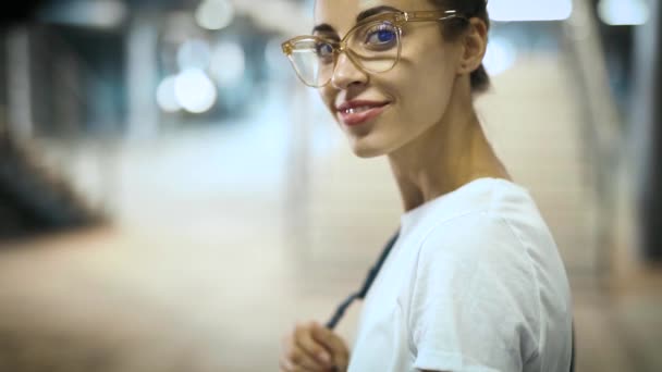 Close-up retrato de jovem sorrindo mulher bonita na moda em óculos transparentes posando ao ar livre. câmara lenta — Vídeo de Stock