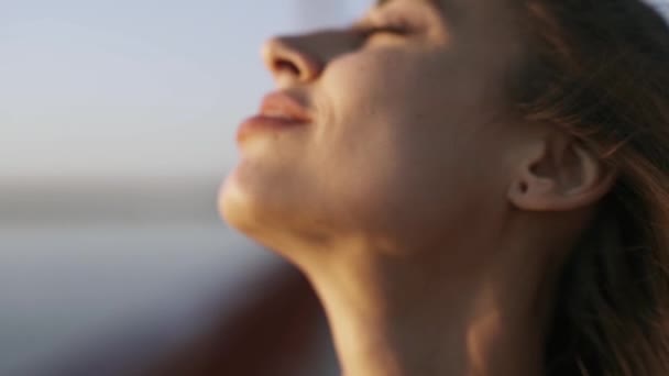 Närbild ansikte unga vacker kvinna njuter av fridfull solnedgång och tittar på solnedgången. hår som flyter i vinden. lugn och avkoppling. Slow motion full HD lager film — Stockvideo