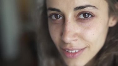 evde genç güzel kadın karışık ırk yakın çekim yüzü. kadın üzgün ve ciddi ilk ve daha sonra sevimli gülümseyerek görünümlü