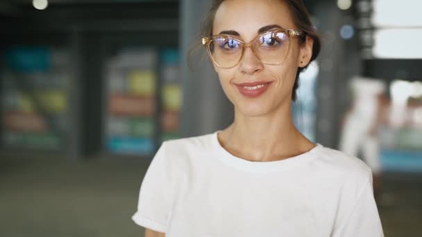 Primer plano retrato de joven sonriente mujer hermosa de moda en gafas transparentes posando al aire libre. cámara lenta — Vídeo de stock