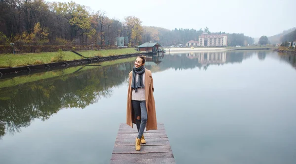 Šťastná žena kráčí po dřevěném molu v parku na podzim. — Stock fotografie