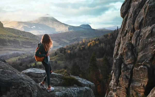 Kvinne som står på kanten av klippen mot soloppgangens bakgrunn – stockfoto
