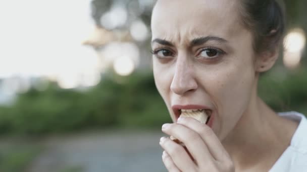 女性は冗談を言って、ワッフルの一部を熱心に噛み切り、面白い顔で食べる様子を描いている — ストック動画