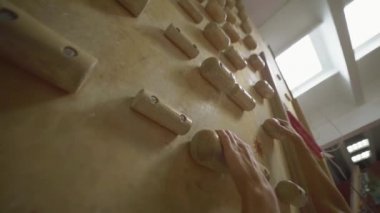 Kadın tırmanışçı, kapalı spor salonuna tırmanmadan önce beyaz tebeşir tozuyla elleri tebeşirliyor. Kadın tırmanmaya hazırlanıyor..