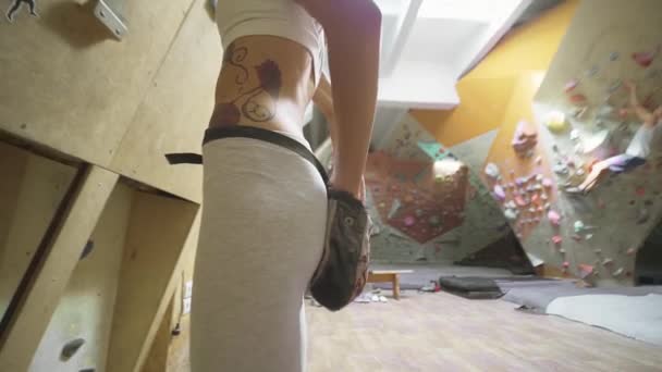 Donna alpinista è gesso mani con polvere di gesso bianco prima di salire in palestra di arrampicata al coperto. donna si prepara a salire . — Video Stock