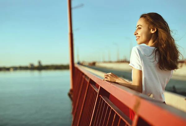 Kırmızı etek ve beyaz t-shirt genç güzel kadın parlak yaşam tarzı portre, poz, köprü üzerinde parlak kırmızı bir zemin üzerinde duran. — Stok fotoğraf