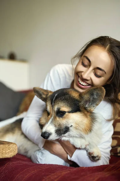 Porträtt av glad leende kvinna med hennes söta walesiska Corgi hund liggande på soffan hemma, ålägga morgon helgen. Fokus på hunden. — Stockfoto