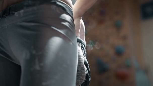 Kadın tırmanışçı, kapalı spor salonuna tırmanmadan önce beyaz tebeşir tozuyla elleri tebeşirliyor. Kadın tırmanmaya hazırlanıyor.. — Stok video