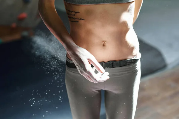 Woman climber is chalking hands with white chalk powder before climb in indoor climbing gym. woman getting ready to climbing. — Stock Photo, Image