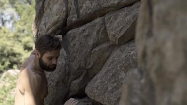 atletik adam kaya tırmanıcı bir uçuruma tırmanıyor, ulaşan ve tutma tutun, belay halat takarak.