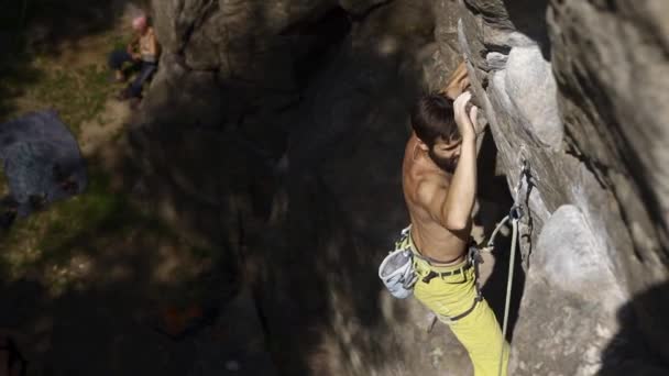 Atlético homem rocha alpinista sobe em um penhasco, atingindo e agarrar segurar . — Vídeo de Stock