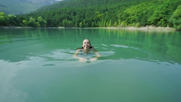 Bela mulher feliz sexy esbelta em roupa de banho azul relaxante, nadando e desfrutando de água doce no lago da montanha no dia de verão ensolarado quente . — Vídeo de Stock