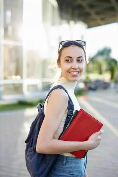 Bella donna felice con uno zaino che va al college. Giovane studentessa universitaria con libri nel campus . — Foto Stock