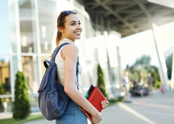 Bella donna felice con uno zaino che va al college. Giovane studentessa universitaria con libri nel campus . — Foto Stock