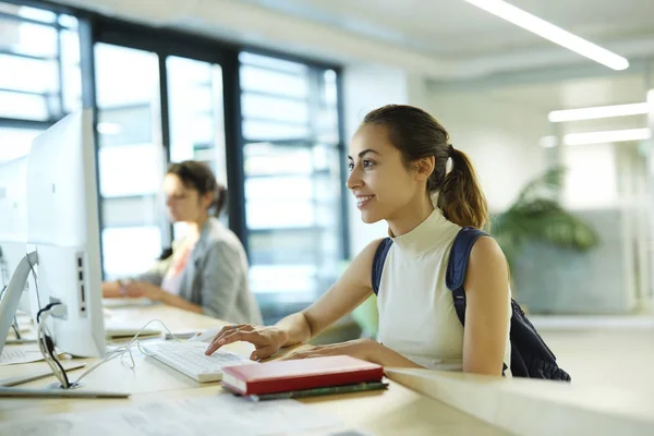 Beautiful happy young woman with a backpack and notebooks inside a college campus. Young female university student with books in campus. — Stock Photo, Image