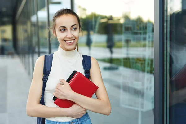 Bella donna felice con uno zaino che va al college. Giovane studentessa universitaria con libri nel campus . — Foto Stock