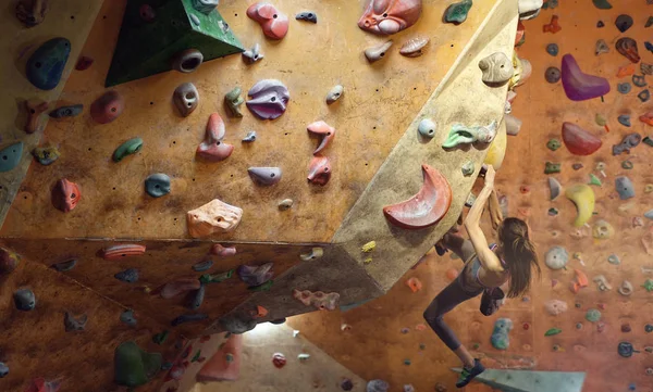 Jonge vrouw Rotsklimmer is klimmen bij Binnen klimmen Gym. slanke mooie vrouw oefening op indoor klimmen Gym Wall — Stockfoto