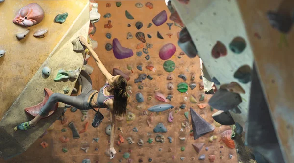 Jonge vrouw Rotsklimmer is klimmen bij Binnen klimmen Gym. slanke mooie vrouw oefening op indoor klimmen Gym Wall — Stockfoto