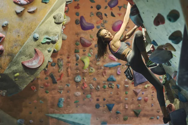 Giovane alpinista femminile Arrampicata Interna palestra di arrampicata. sottile bella donna esercizio fisico a Indoor Climbing Gym Wall. — Foto Stock