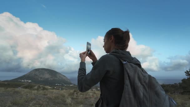 Kvinna vandrare ser fantastisk vacker molnig solnedgång himmel och ta foto med mobiltelefon — Stockvideo