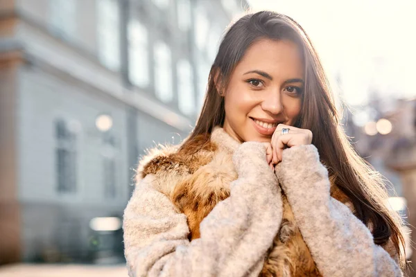 Closeup portrait of beautiful young woman in warm sweater posing outdoors in city at sunny autumn day — Stock Photo, Image