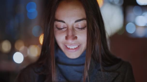 Primo piano di prety donna sorridente utilizzando smartphone a piedi di notte città — Video Stock