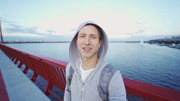Atractivo sonriente hombre blogger en sudadera con capucha haciendo video selfie — Vídeos de Stock