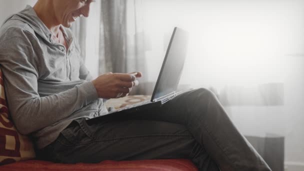 Uomo seduto a casa sul divano utilizzando il computer portatile — Video Stock