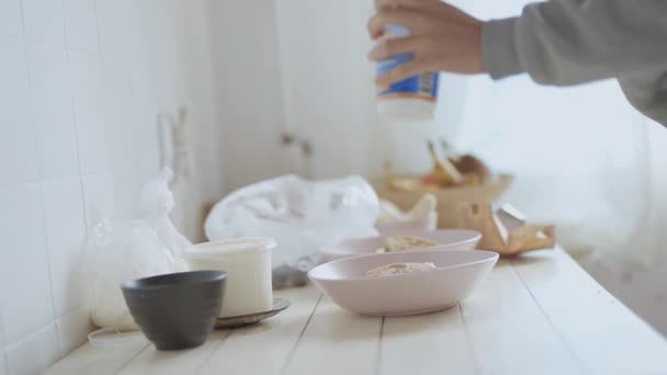 Pink bowls with pancakes and cutted fruits for fruit salad on white wooden table. unrecognizable woman put in sour cream to the bowls. — Stock Video