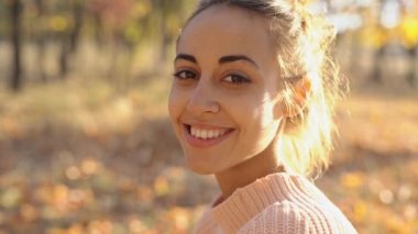 Autamn Ormanı 'nda örülü pembe süveter giyen ve gülümseyen güzel bir kızın aşırı yakın çekimi.