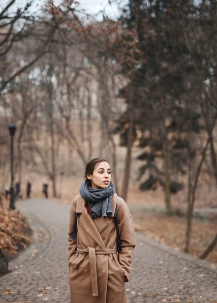 Осенний открытый портрет красивой молодой женщины, гуляющей в осеннем парке, в бежевом пальто и с теплым вязаным шарфом . — стоковое фото