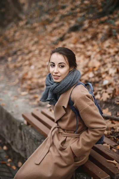 Осенний открытый портрет красивой молодой женщины в осеннем парке, сидящей на скамейке и наслаждающейся осенним пейзажем . — стоковое фото