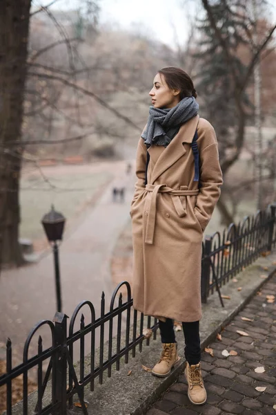 Осенний открытый портрет красивой молодой женщины, гуляющей в осеннем парке, в бежевом пальто и с теплым вязаным шарфом . — стоковое фото