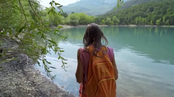 Mujer excursionista disfrutando de un paisaje con lago de montaña . — Vídeo de stock