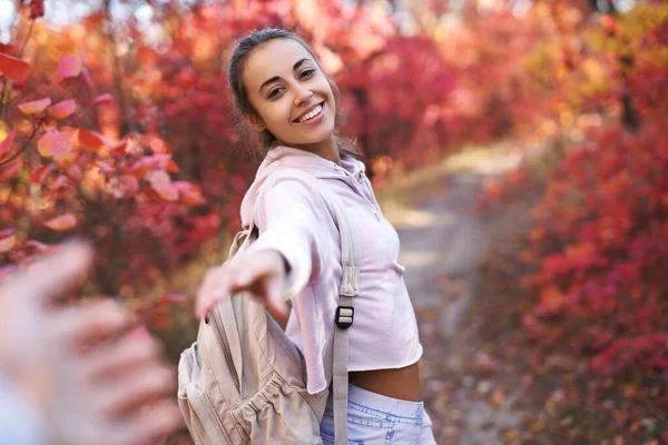 First person view of a happy smiling young woman, turns around at camera, walking in autumn park with colorful leaves on fall nature background. — Stock Photo, Image