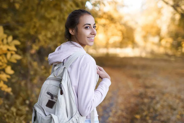 Mujer de otoño se da la vuelta en la cámara con una sonrisa encantadora, caminando en el parque de otoño con hojas coloridas en el fondo de la naturaleza de otoño . — Foto de Stock