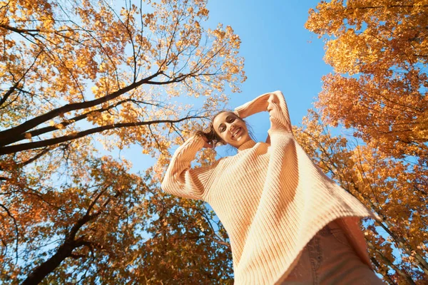 Pohja näkymä iloinen hymyilevä tyttö etsii alas syksyllä puistossa värikkäitä lehtiä syksyllä luonto tausta — kuvapankkivalokuva