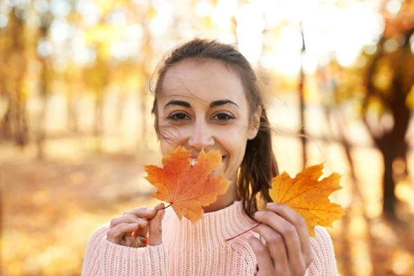 Utendørs portrett av unge smilende kvinner som holder høstblader i høstparken med fargerike blader på høstens naturbakgrunn . – stockfoto