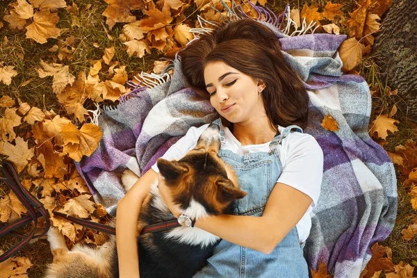 Sorrindo mulher feliz em conjunto com galês Corgi Pembroke cão em um parque ao ar livre. Jovem dona abraçando animal de estimação no parque no outono sobre o fundo de folhagem laranja . — Fotografia de Stock